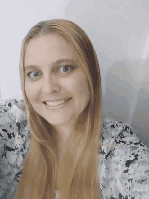 a woman with long blonde hair and blue eyes is smiling