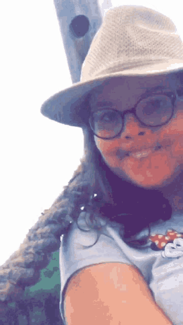 a woman wearing glasses and a hat is smiling