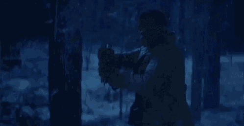 a man is holding a blue light saber in a forest .