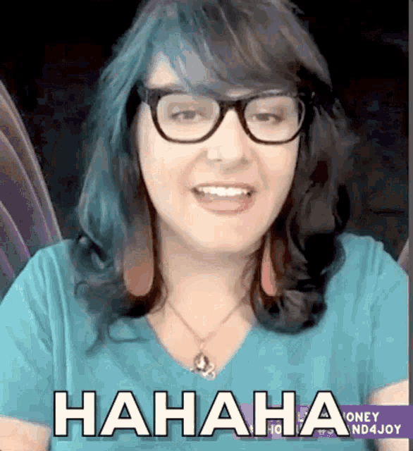 a woman with blue hair and glasses is laughing while wearing a necklace .