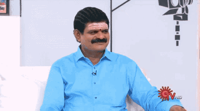 a man in a blue shirt is sitting in front of a tv screen that says gtv