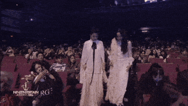 a woman in a white dress stands in front of a microphone at the nineentertainment awards