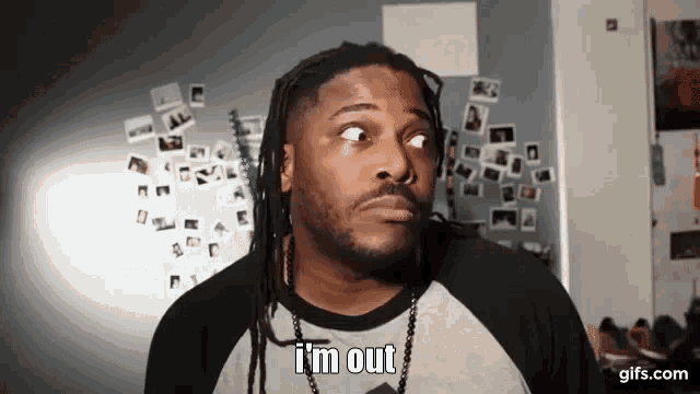 a man with dreadlocks says i 'm out in front of a wall with pictures on it