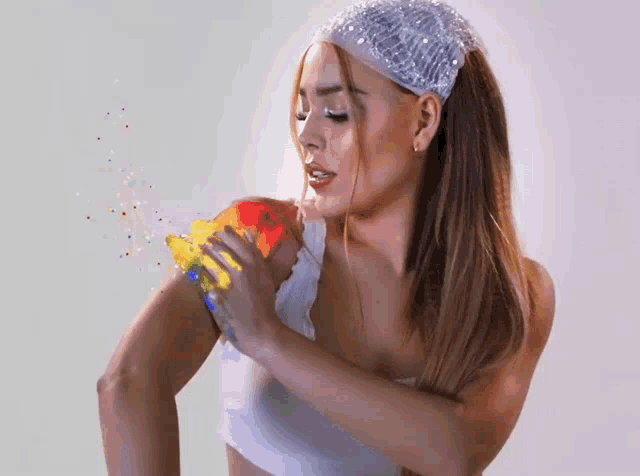a woman with a headband on her head is holding a rainbow colored object