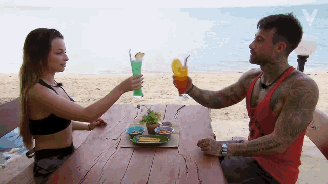 a man and a woman are sitting at a table holding drinks