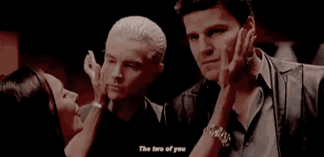 two men are standing next to each other and one of them is holding another man 's arm .