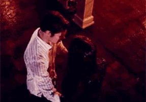 a man in a striped shirt is kneeling down next to a woman on a red floor .