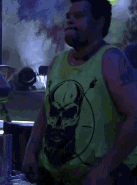 a man wearing a green tank top with a skull and arrows on it