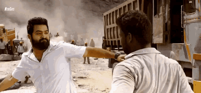 a man with a beard is being punched in the face by another man in a white shirt