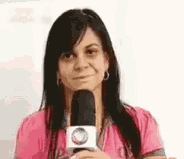 a woman is holding a microphone in front of her face and smiling .