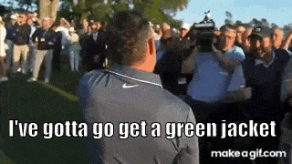 a man is standing in front of a crowd of people on a golf course talking to them .