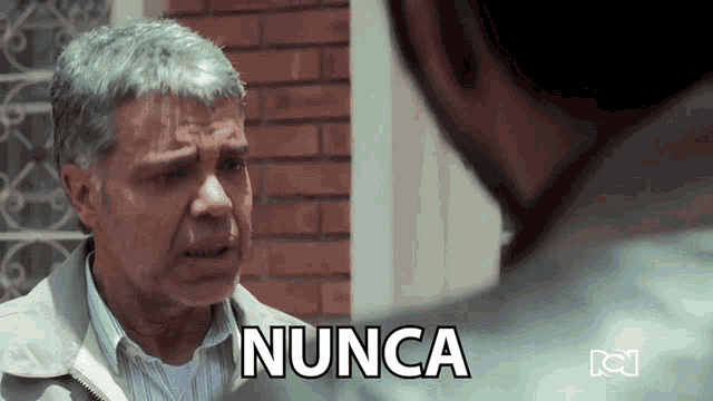 a man is talking to another man and the word nunca is on the screen behind him