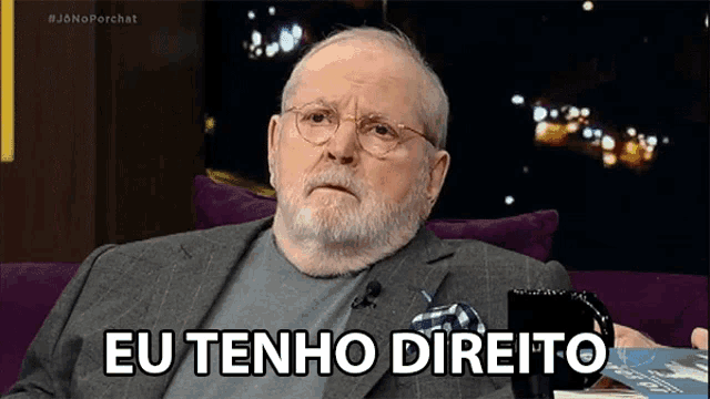 a man with glasses and a beard is sitting on a couch and saying eu tenho direito