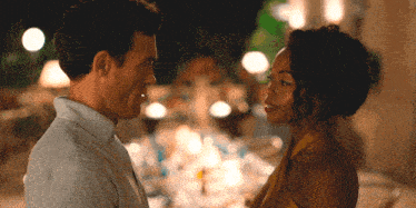 a man and a woman are looking at each other with a table in the background