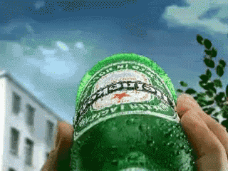 a person is holding a bottle of heineken in their hand