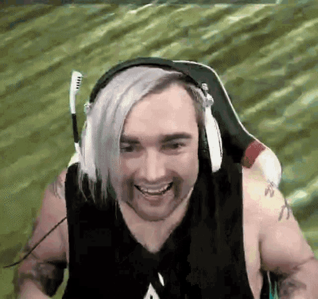 a man wearing headphones and a tank top is smiling while sitting in a chair .