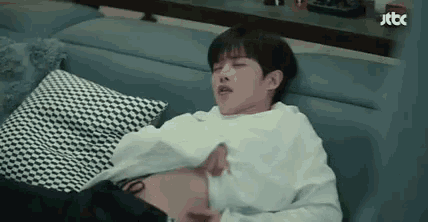 a man is laying on a couch with his shirt off and holding his belly .