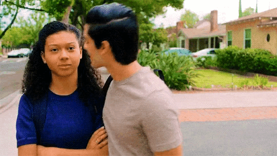 a man is kissing a woman on the cheek while standing on the sidewalk .