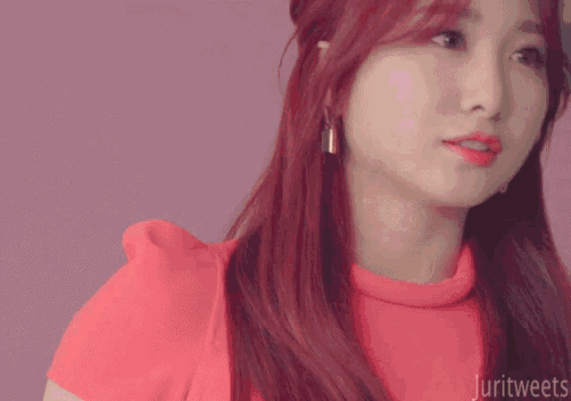a woman with red hair is wearing a pink top and earrings