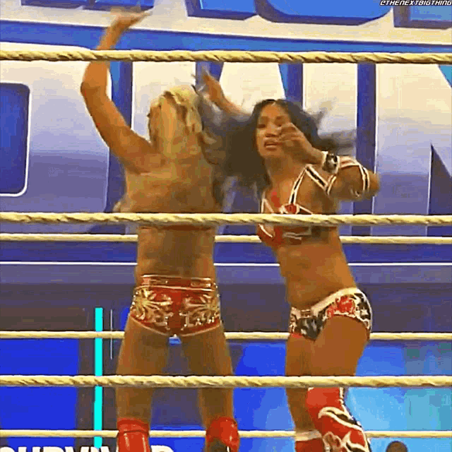 two women are wrestling in a ring and one of them is wearing red shorts .