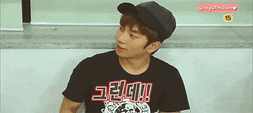 a young man wearing a hat and a t-shirt is sitting on a staircase .