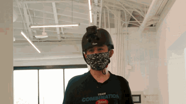 a man wearing a mask and a helmet has a team combination shirt on