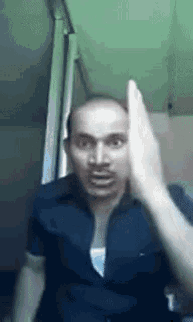 a man in a black shirt is making a funny face with his hand