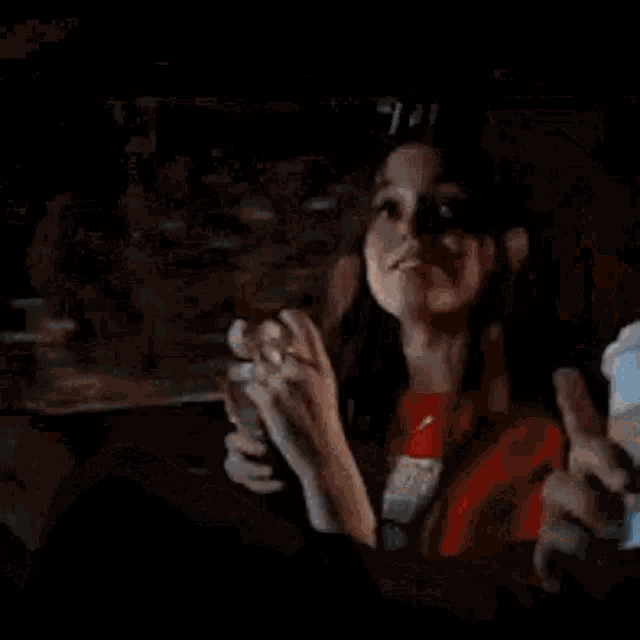 a woman is sitting in the back seat of a car eating a hamburger and drinking a cup of coffee .