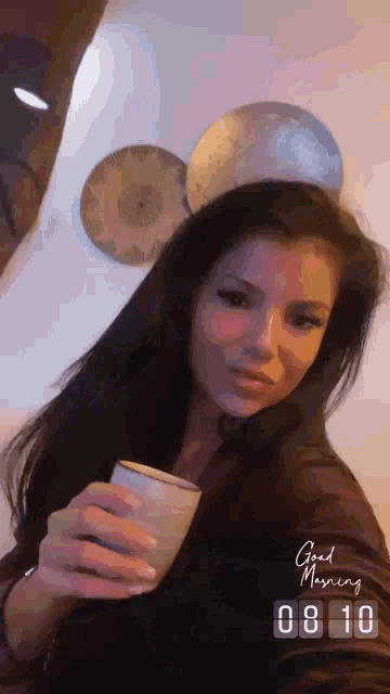 a woman holding a cup with the words good morning written on the bottom