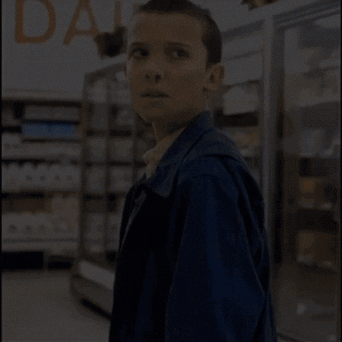 a woman in a blue jacket stands in front of a dairy section
