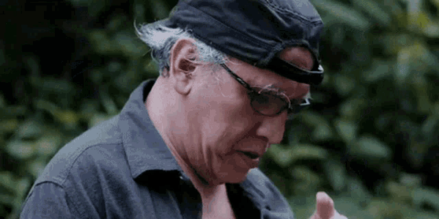 a man wearing a black hat and glasses is looking down .