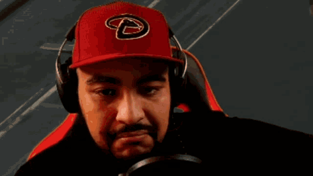 a man wearing headphones and a red hat with the letter t on it