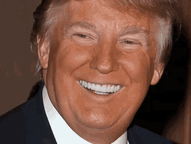 a close up of donald trump 's face with a smile on his face
