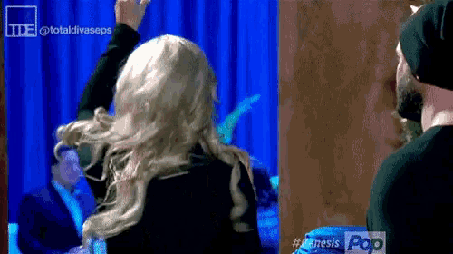 a woman in a wig stands in front of a blue curtain with the words totaldivaseps on the bottom right