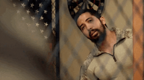 a man with a beard is standing in front of a dart board with the number 15 on it .