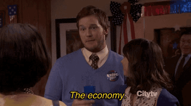 a man in a blue sweater says the economy while talking to a woman