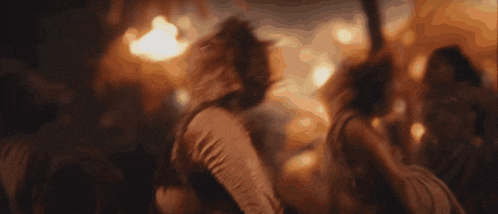 a group of people are dancing in a dark room with fire behind them .