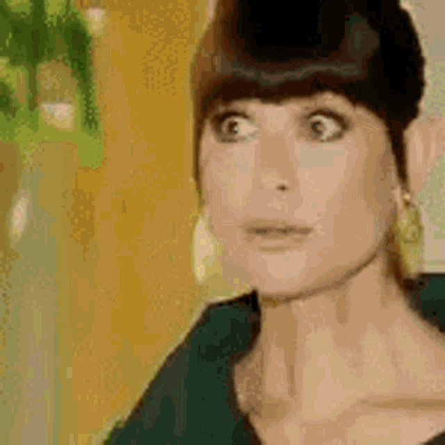 a woman with a surprised look on her face is wearing earrings and a green shirt .