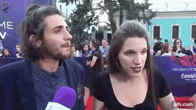 a man and a woman are talking on a red carpet .