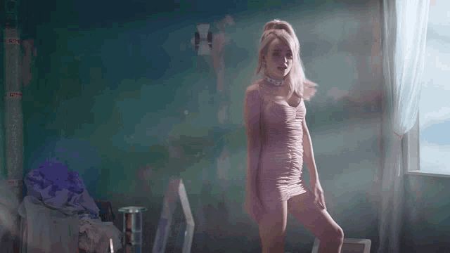a woman in a pink dress is standing in a room with a window