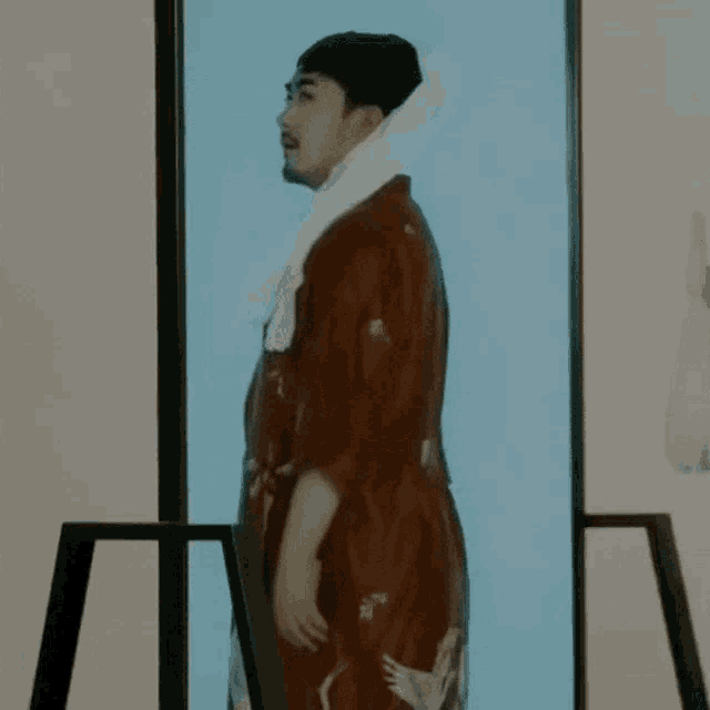 a man in a red robe with a white towel around his neck