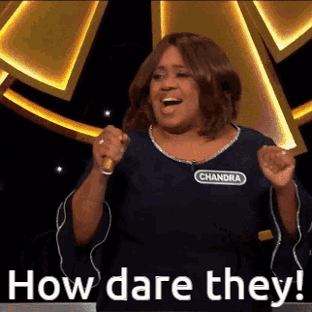 a woman with the name chandra on her shirt is holding a microphone and saying how dare they .