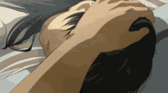 a close up of a person laying on a bed with their hand on their head