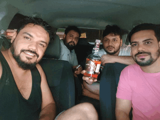 a man in a pink shirt holds a bottle of jack daniel 's
