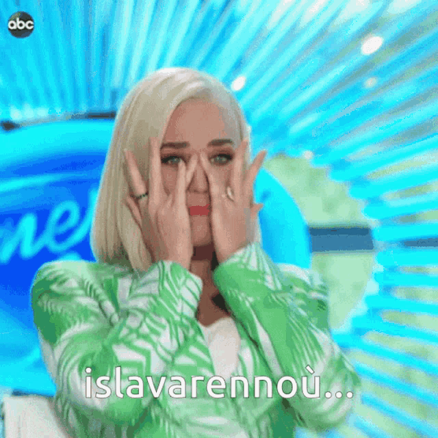 a woman in a green jacket is covering her face with her hands and says " islavarennou " in a foreign language