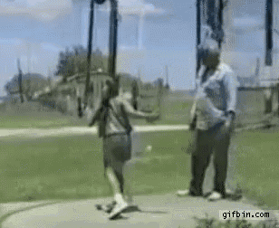 a man is standing next to a girl swinging on a swing set .