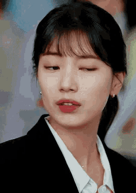 a close up of a woman wearing a black suit and white shirt .