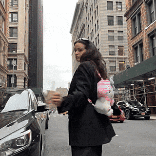 a woman wearing a hello kitty backpack is walking down the street