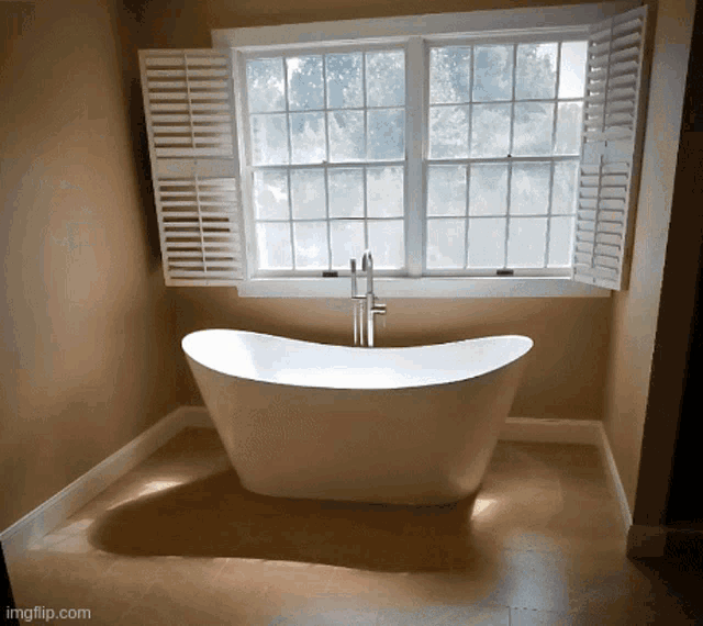 a bathtub in a bathroom next to a window with shutters on it