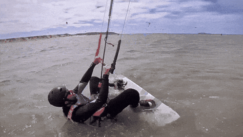 a man in a wet suit is laying on a surfboard